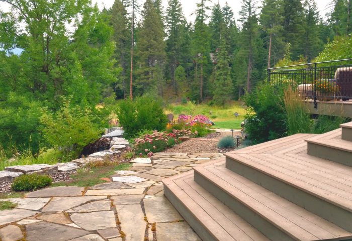 Wooden stairway alongside a rock-lined garden bed with flowering plants, finished landscape design by Beargrass Landscape Architecture