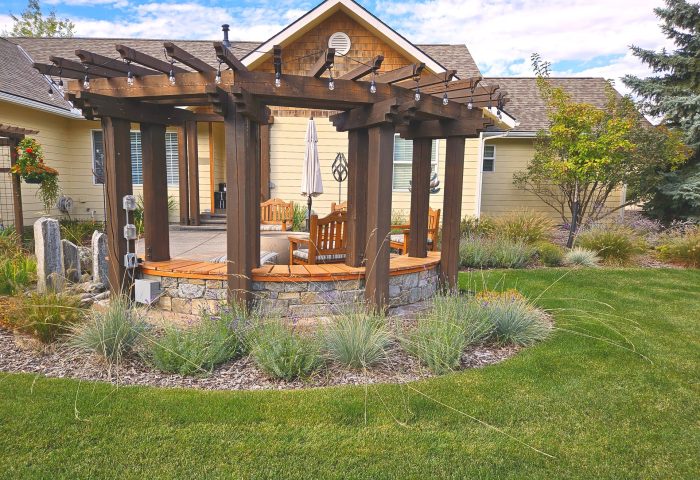 Circular pergola patio with stone base and native ornamental grasses, finished landscape design for a Bigfork residential project by Beargrass Landscape Architecture