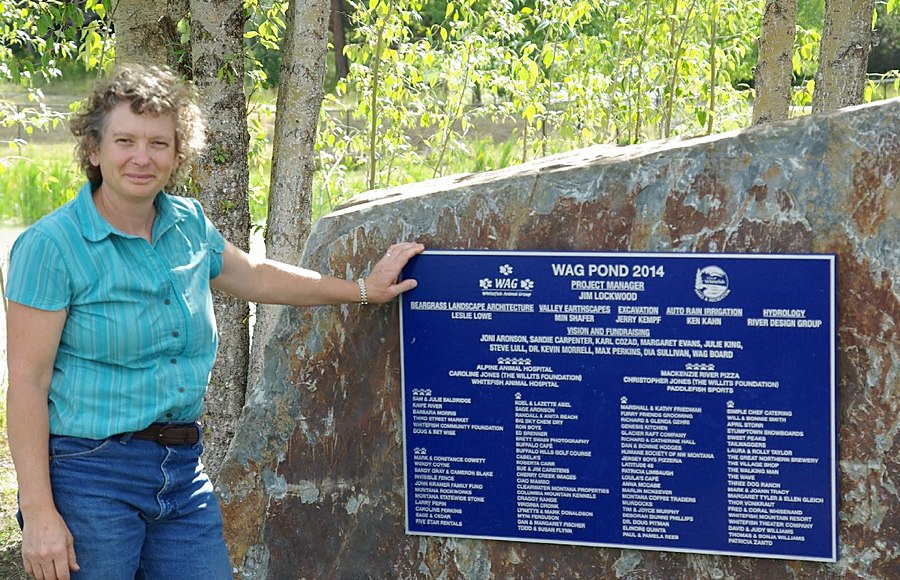 Leslie Lowe beside the WAG Pond dedication plaque crediting Beargrass Landscape Architecture